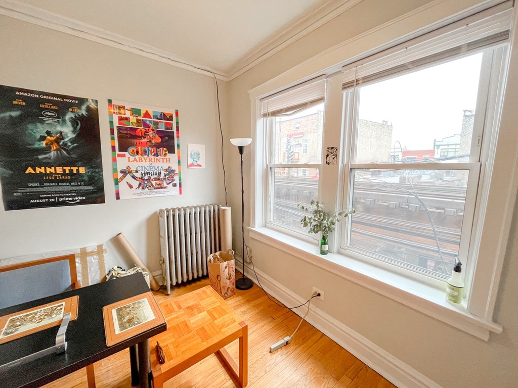 a living room with two windows and a desk and a radiator