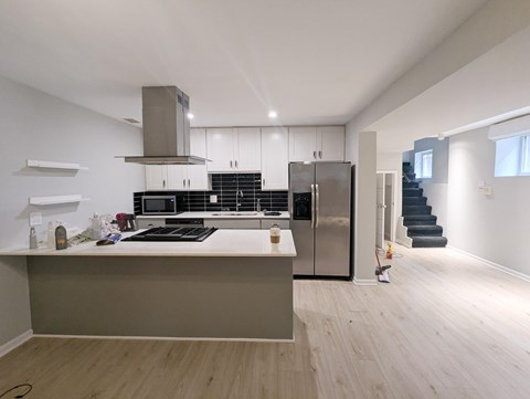 A modern kitchen with a stainless steel refrigerator and a wooden floor.