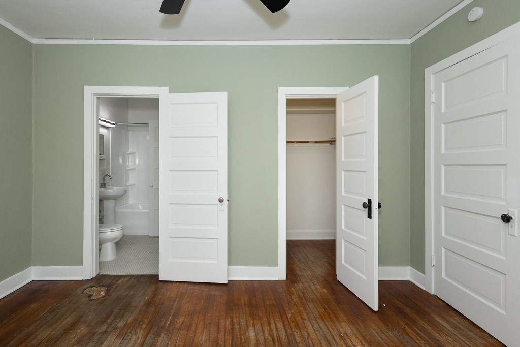 an empty room with two doors open to a bathroom and a toilet