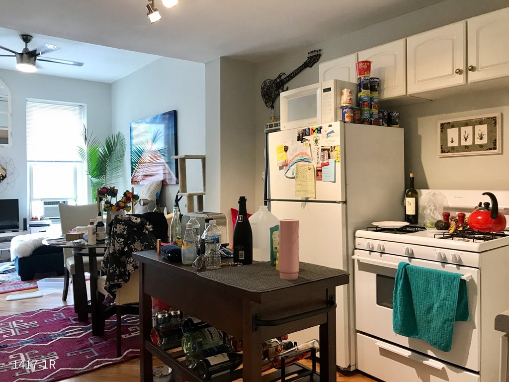 a kitchen with a table and a stove and a refrigerator with a microwave on top of it