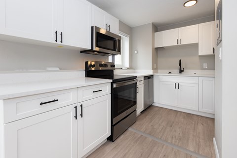 A kitchen with white cabinets and a black stove top oven.