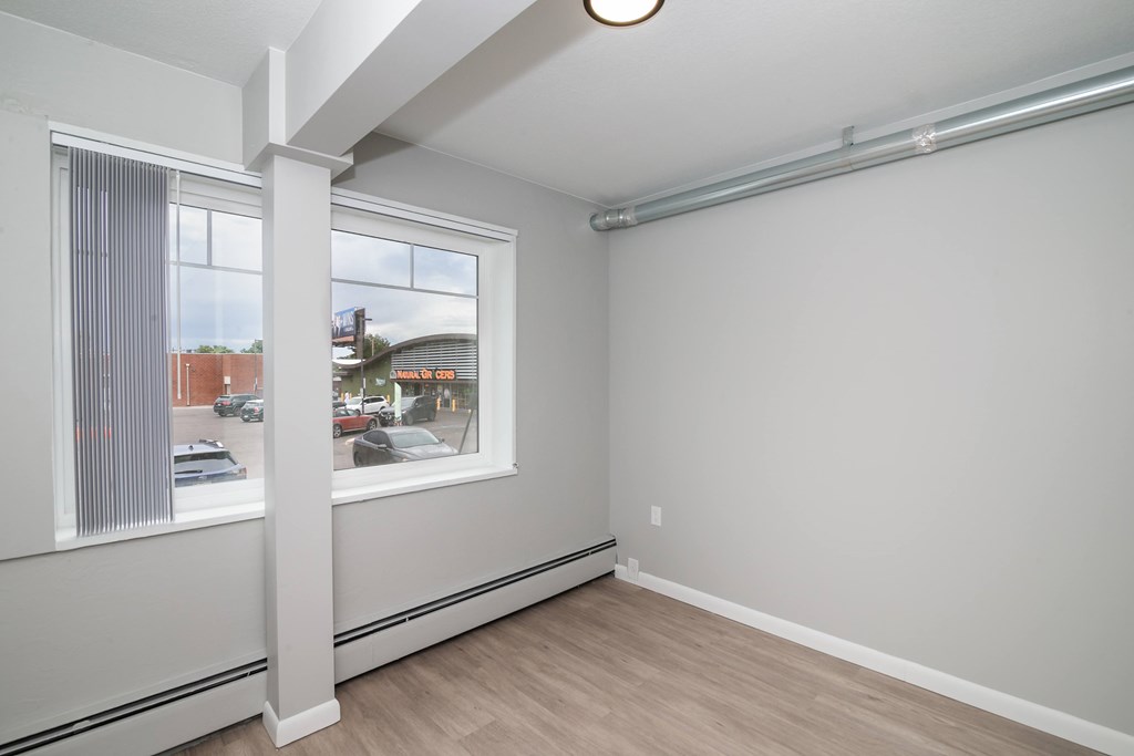 A room with a window and a white wall.