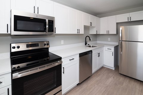 A modern kitchen with white cabinets and stainless steel appliances.