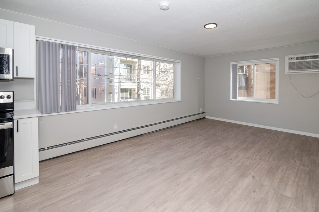 A spacious kitchen with light wood flooring and white cabinetry.
