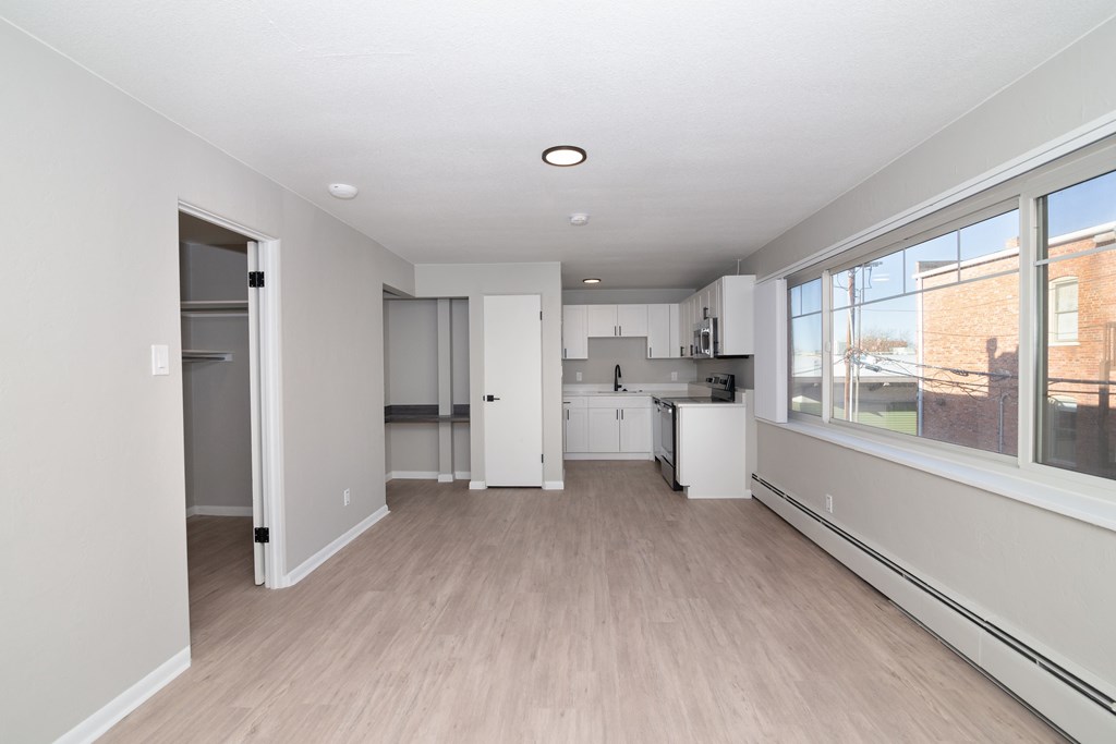 A large empty room with a kitchen area in the background.