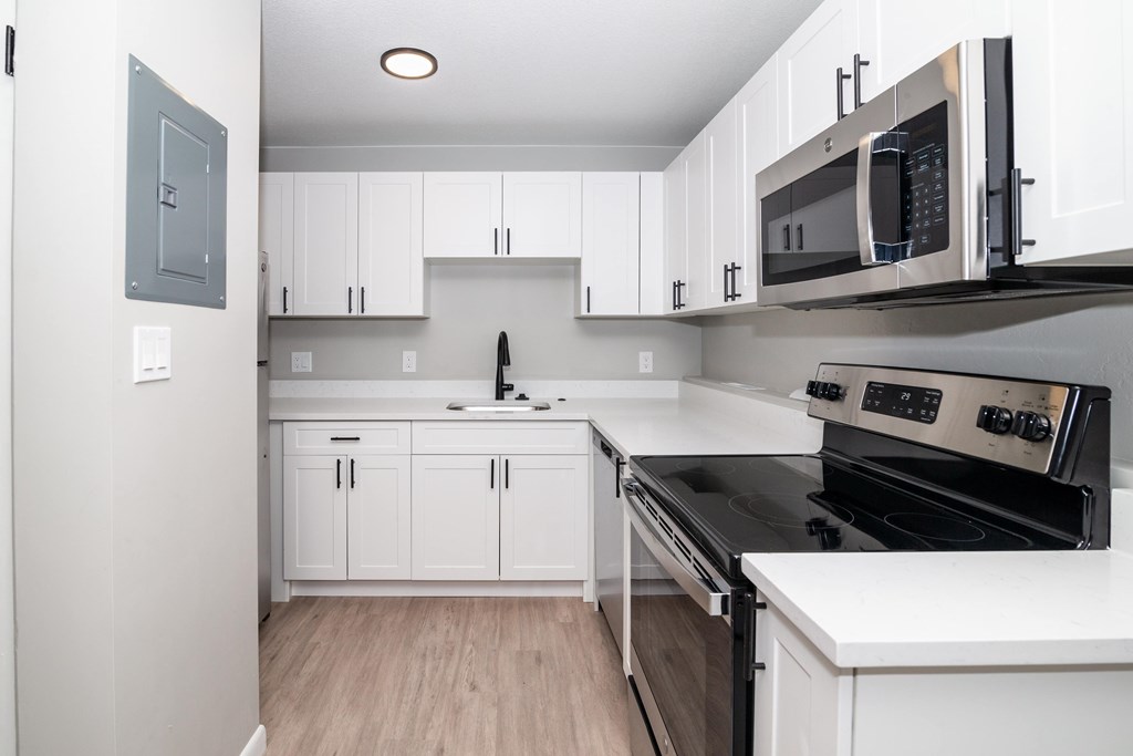 A kitchen with white cabinets and a black stove top oven.