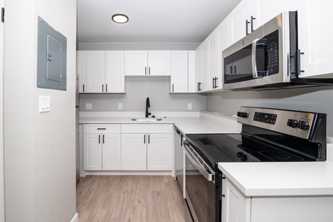 A kitchen with white cabinets and a black stove top oven.