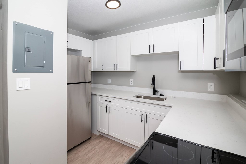 A kitchen with white cabinets and a black stove top.