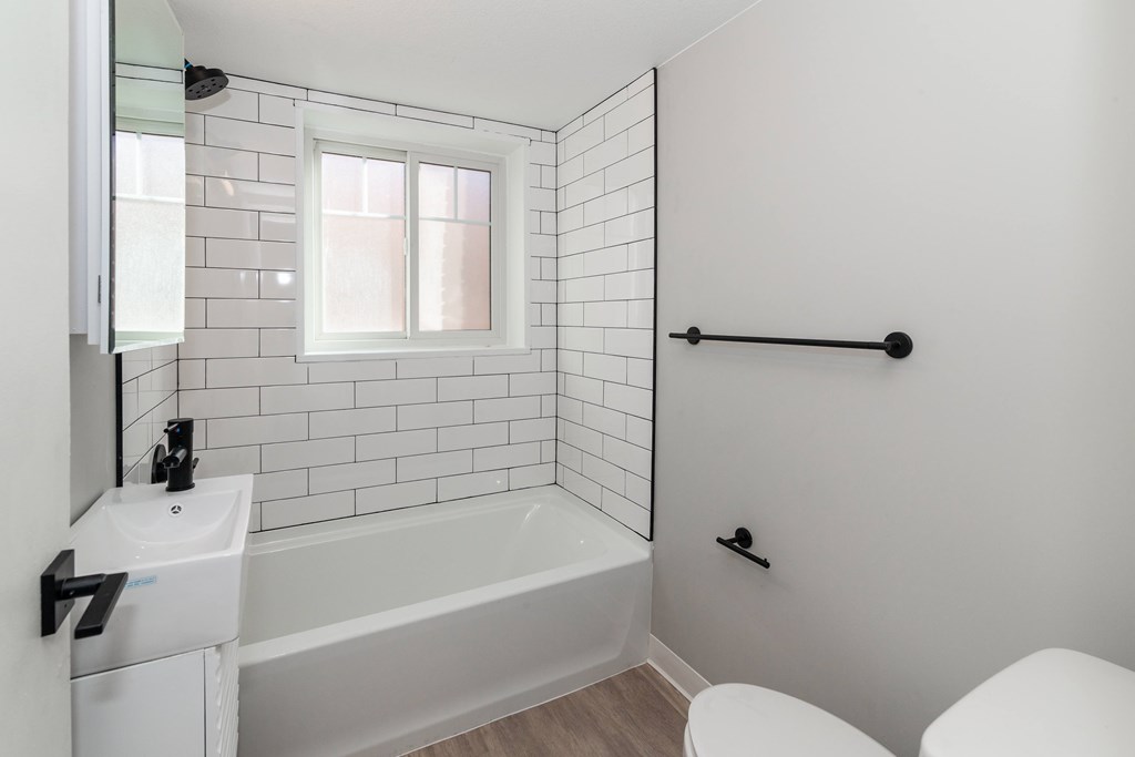 A white bathroom with a tub, sink, and toilet.