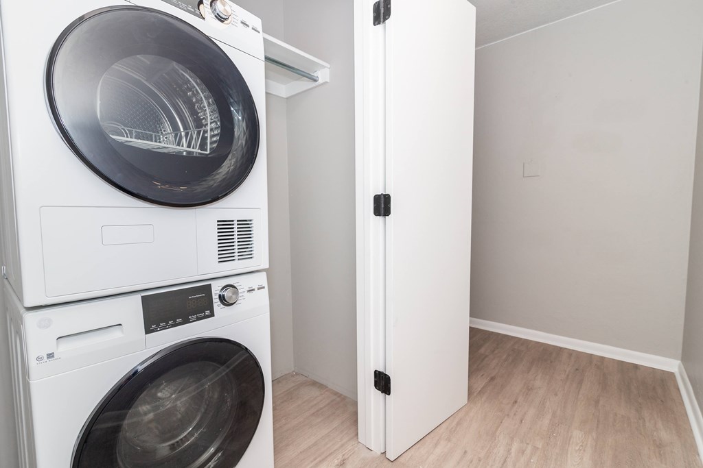 A white washing machine and dryer stacked on top of each other in a small room.