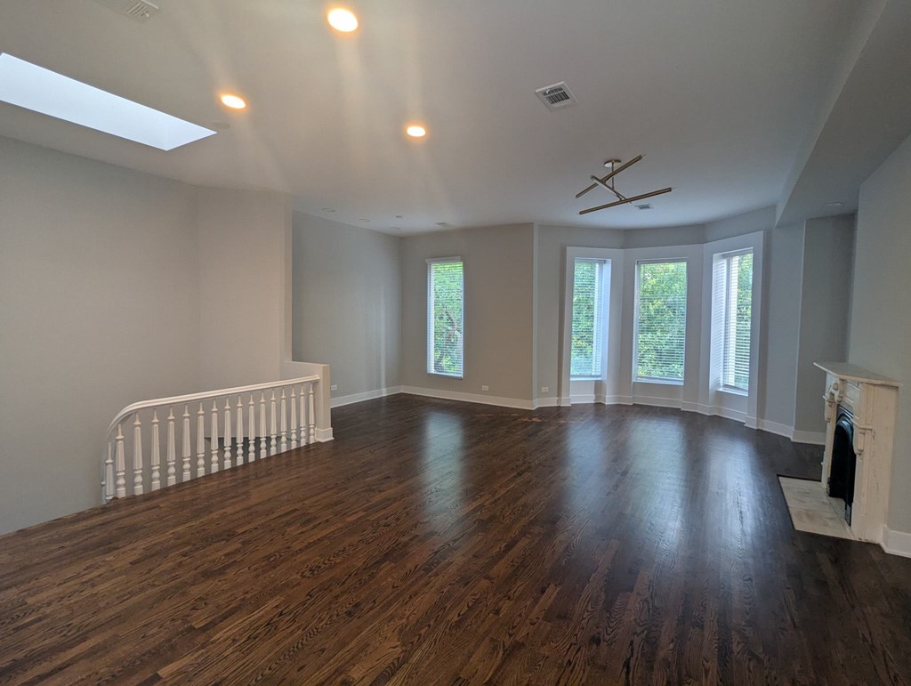 A spacious room with wooden floors and a fireplace.