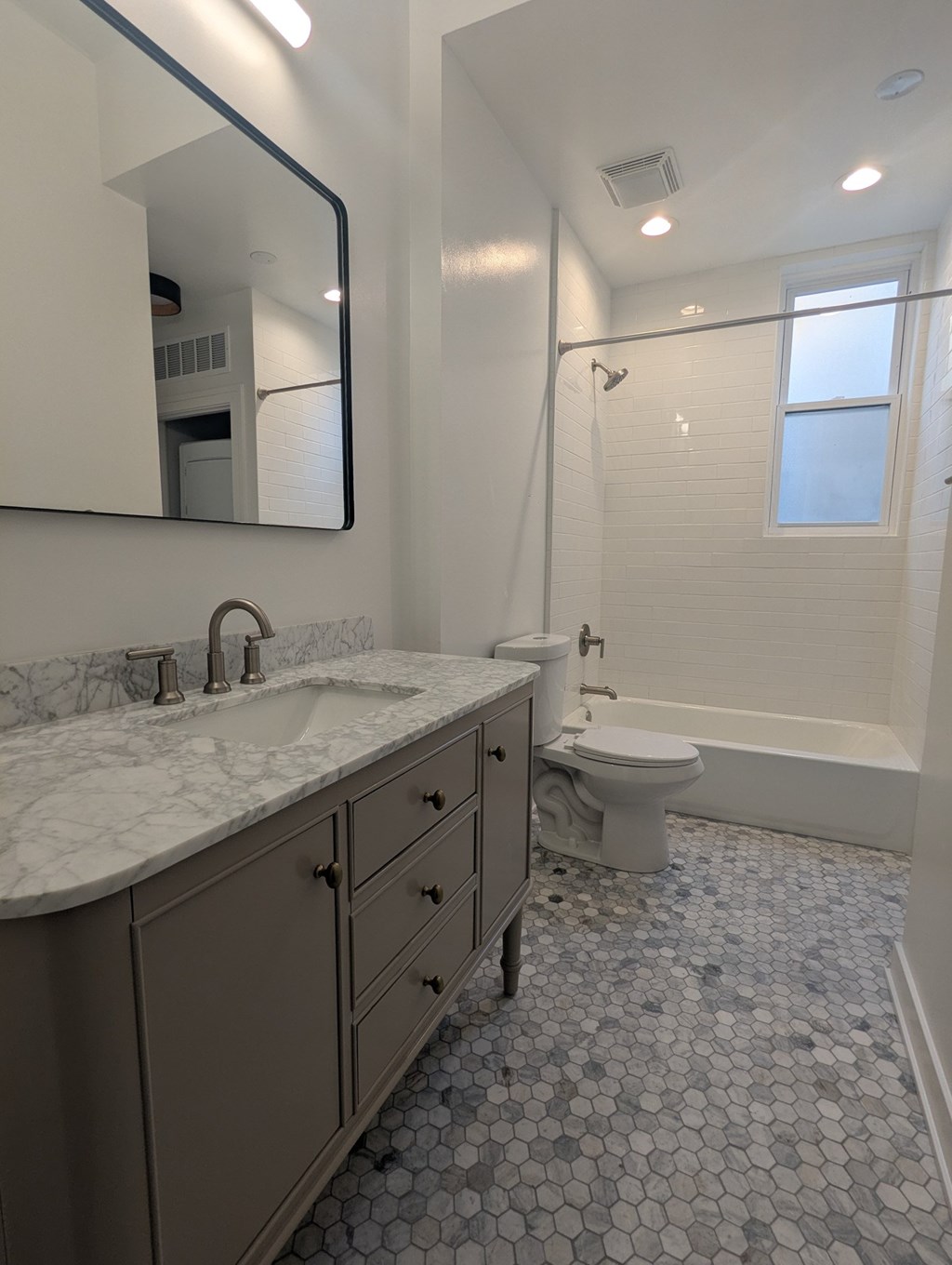 A bathroom with a marble counter top and a large mirror.