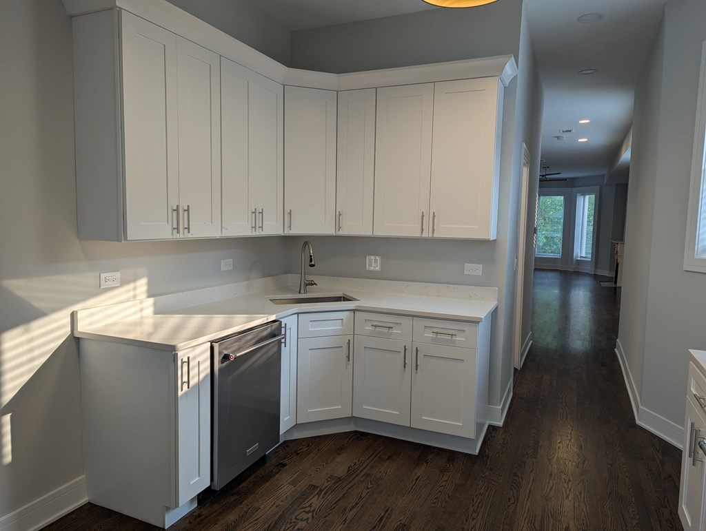 A kitchen with white cabinets and a wooden floor.