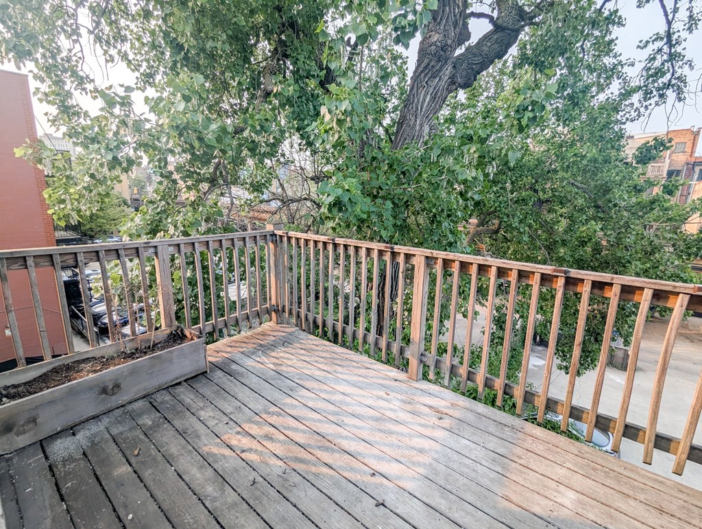 A wooden deck with a railing and trees in the background.