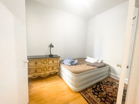 A bedroom with a bed, dresser, and rug.