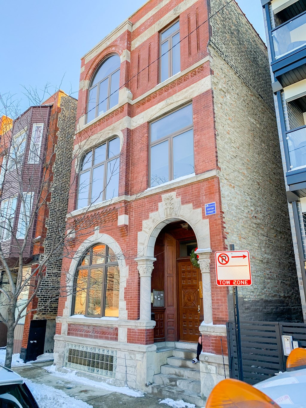 a brick building with a wooden door and a no parking sign