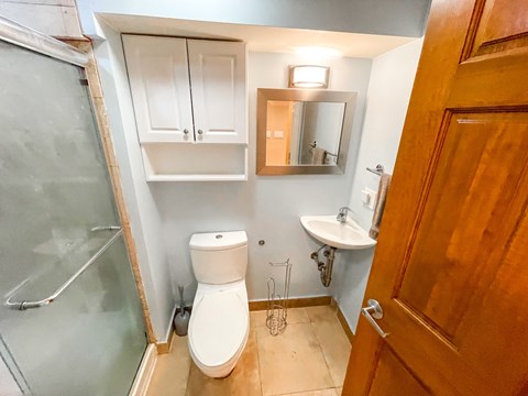 A bathroom with a toilet, sink, and mirror.