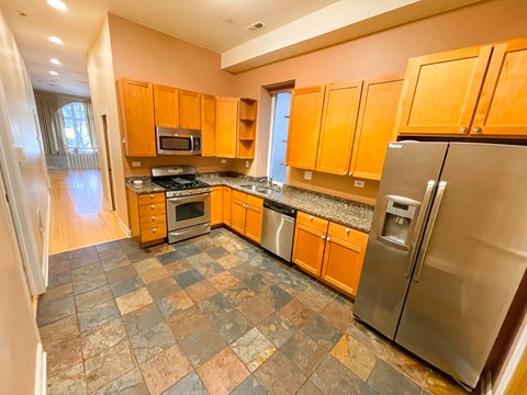 A kitchen with a refrigerator, microwave, oven, and cabinets.