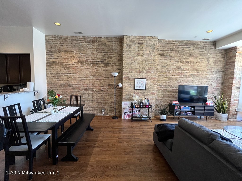 an open living room with a brick wall and a dining room