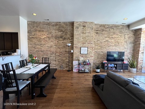 an open living room with a brick wall and a dining room