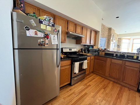 A kitchen with a refrigerator covered in magnets and a stove top oven.