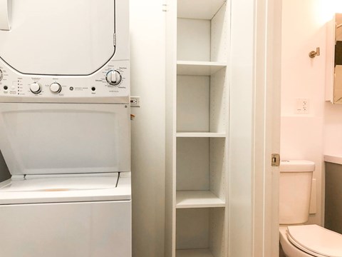 A white oven with a towel hanging on the handle is next to a white toilet.