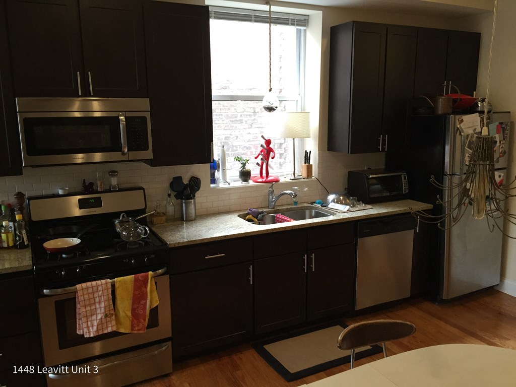 a kitchen with black cabinets and stainless steel appliances and a window