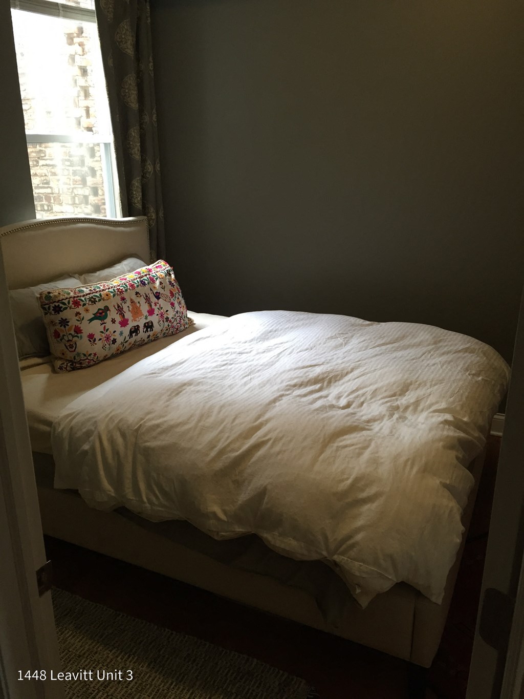 a bed with a white comforter and a pillow and a window
