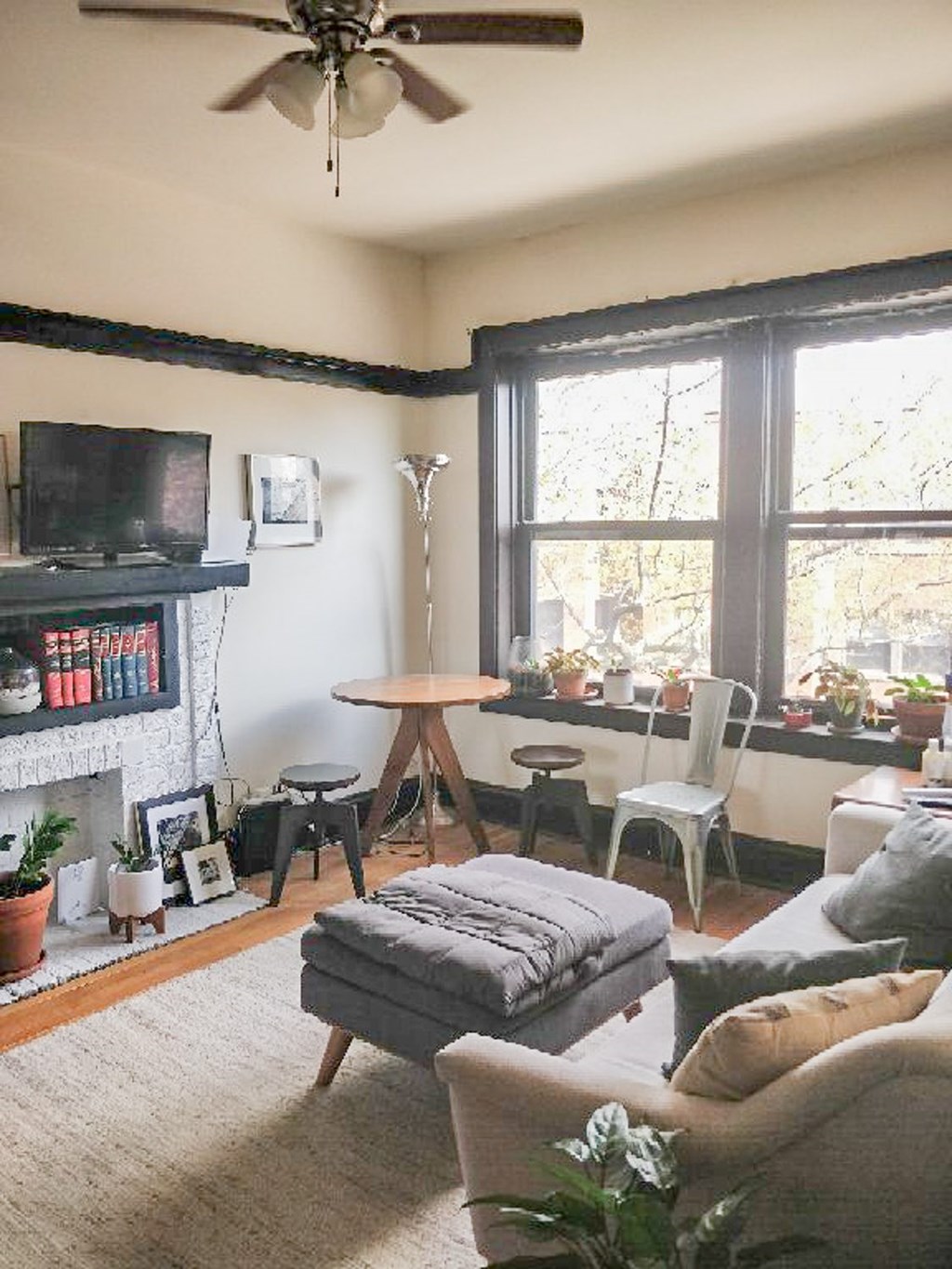 A living room with a grey sofa, a white chair, a wooden table, and a television on a black stand.
