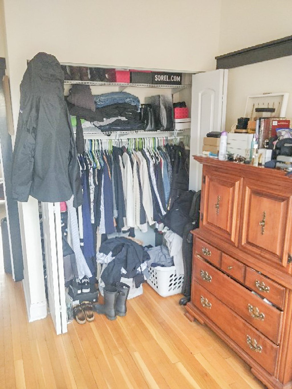 A closet full of clothes and a dresser with a mirror.