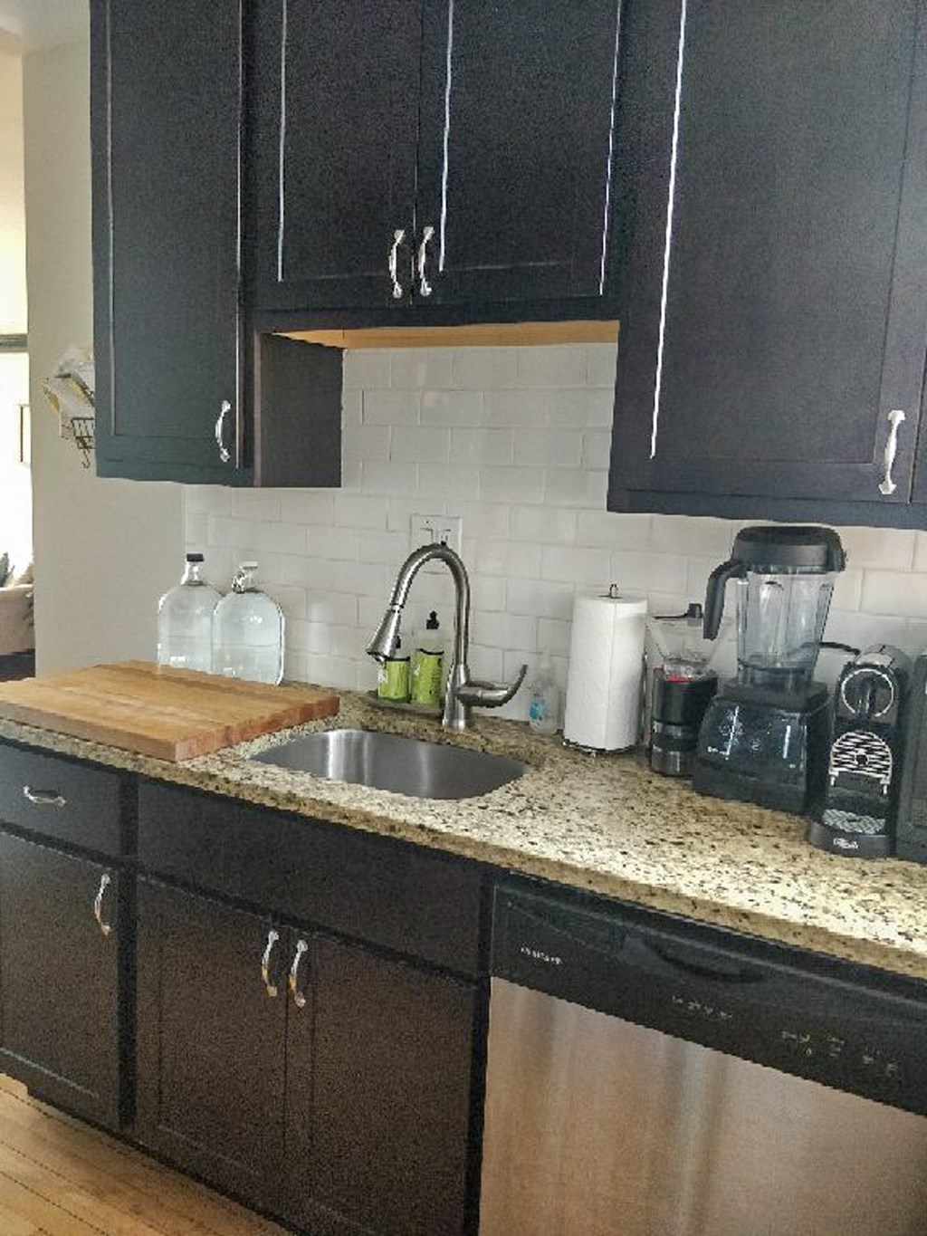 A kitchen with black cabinets and a granite countertop.