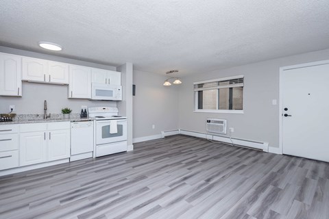 A kitchen with white cabinets and a grey floor.