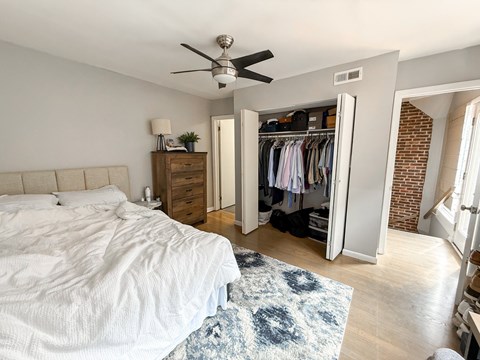 A bedroom with a bed, dresser, and closet.