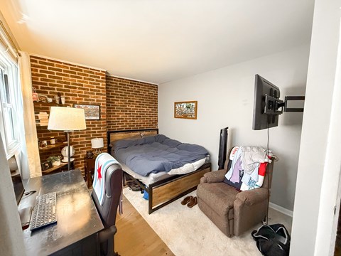 A bedroom with a bed, chair, and a television.