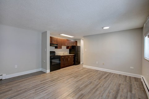 an empty living room and kitchen with wood flooring