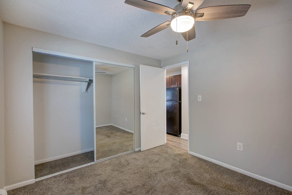 an empty bedroom with a closet and a ceiling fan