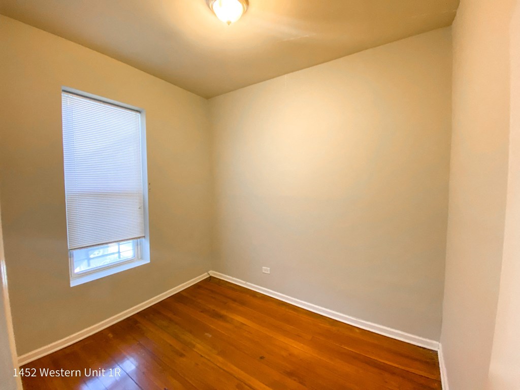 a bedroom with hardwood floors and a window