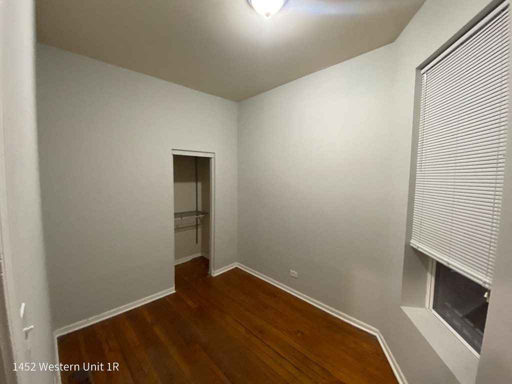 a bedroom with a closet and hardwood floors