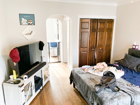A bedroom with a bed, dresser, and a television.