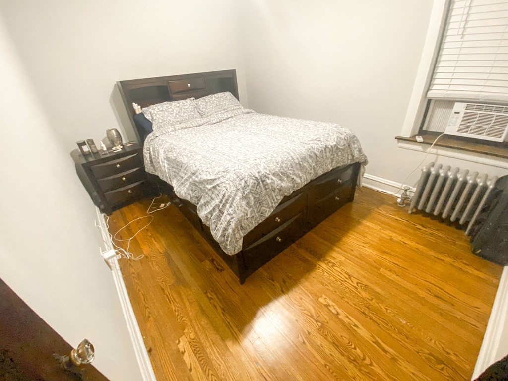 a bedroom with a bed and a dresser on a wooden floor