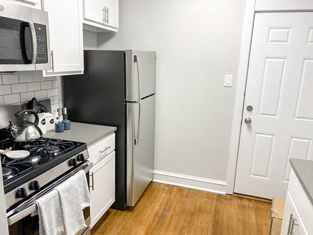 A black refrigerator sits next to a stove in a kitchen.