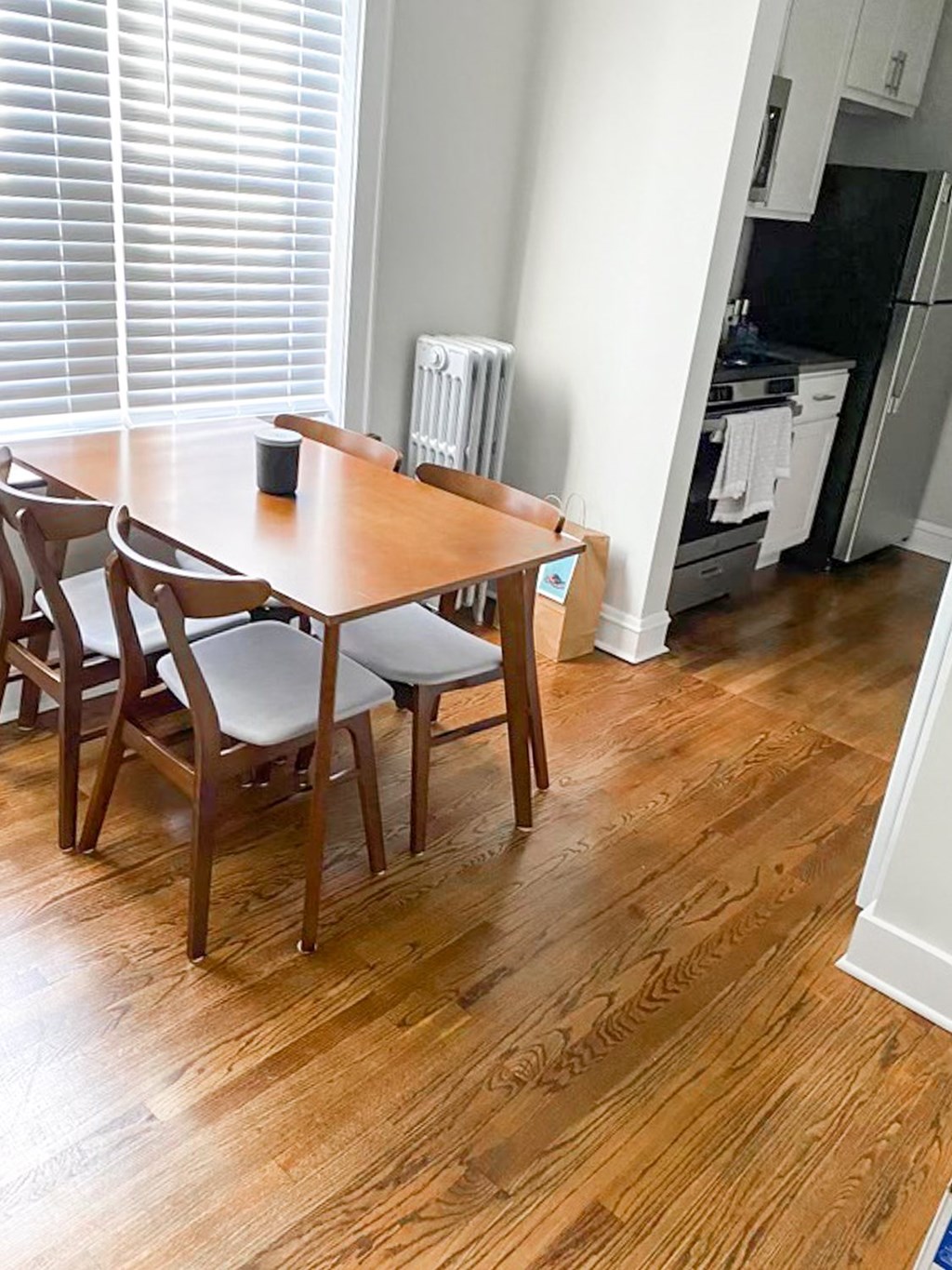 A brown wooden dining table with four chairs in a room.
