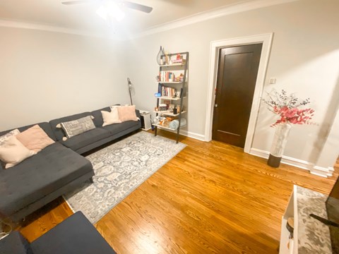 A living room with a black couch and a wooden floor.