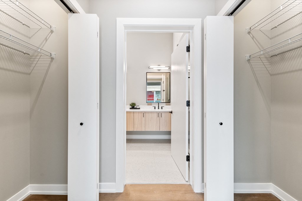a walk in closet in a home with a bathroom and a sink