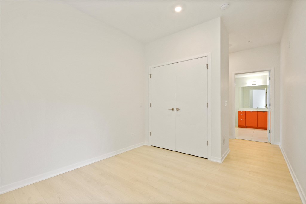 a living room with white walls and wooden floors and a white door