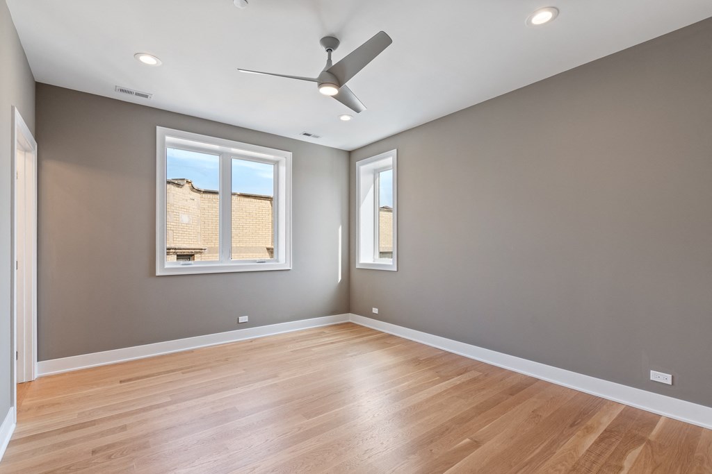 an empty living room with wood floors and a ceiling fan