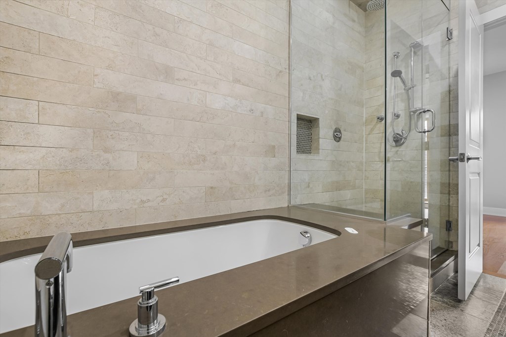 A bathroom with a beige tiled wall and a glass shower stall.