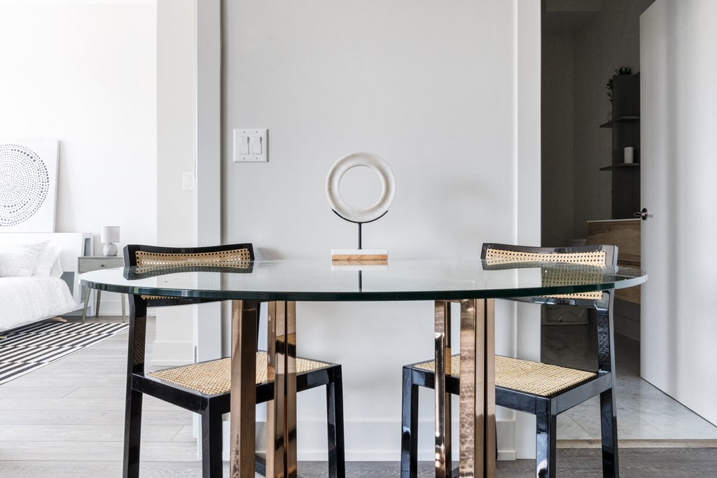 A round glass dining table with two chairs and a mirror 
