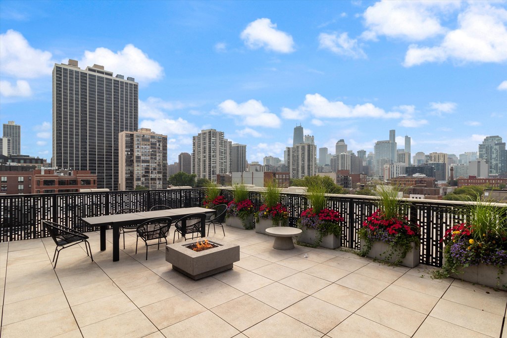 the terrace on the top of the building has a table and chairs and a fire pit