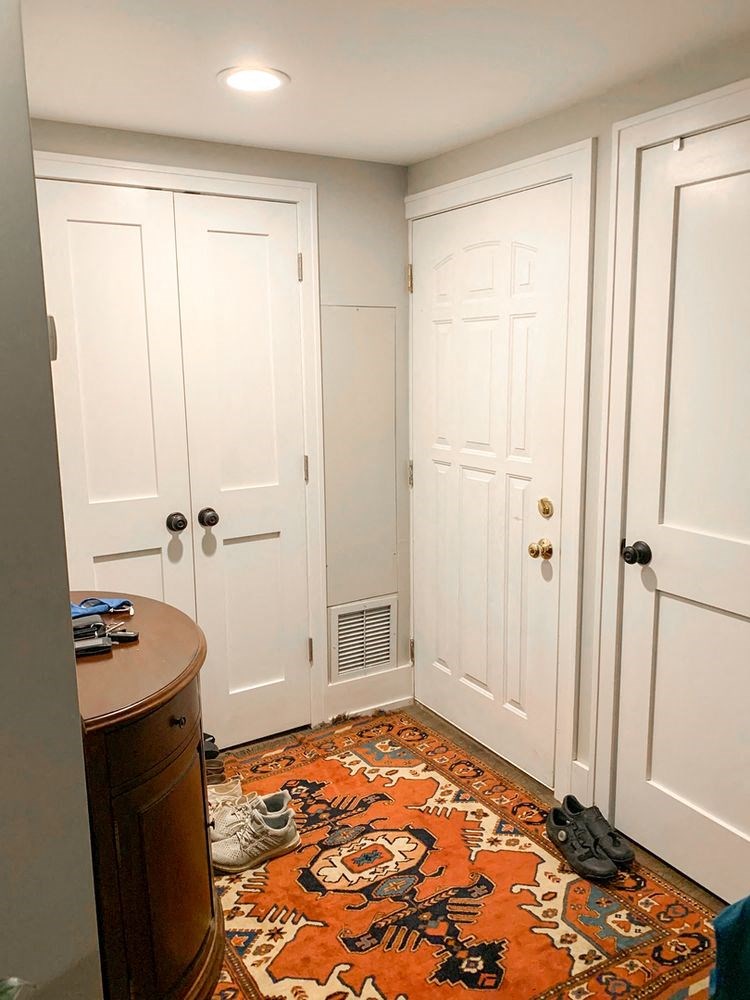 a closet with white doors and a orange rug